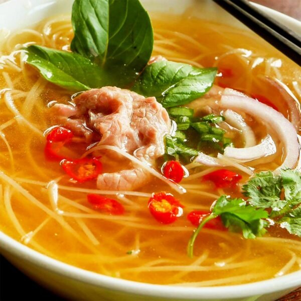A bowl of noodle soup with fresh herbs and aromatic broth